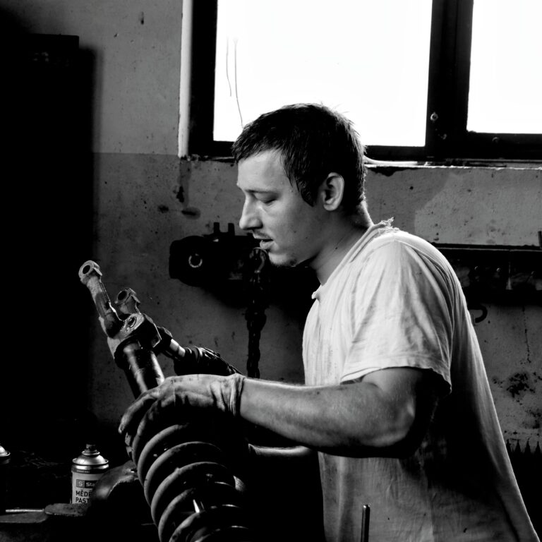 A black and white portrait of a focused auto mechanic working in a workshop.